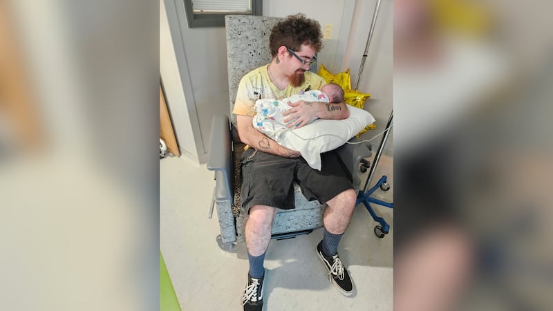 Cooper Miller, 20, holds his daughter at Children's Hospital.