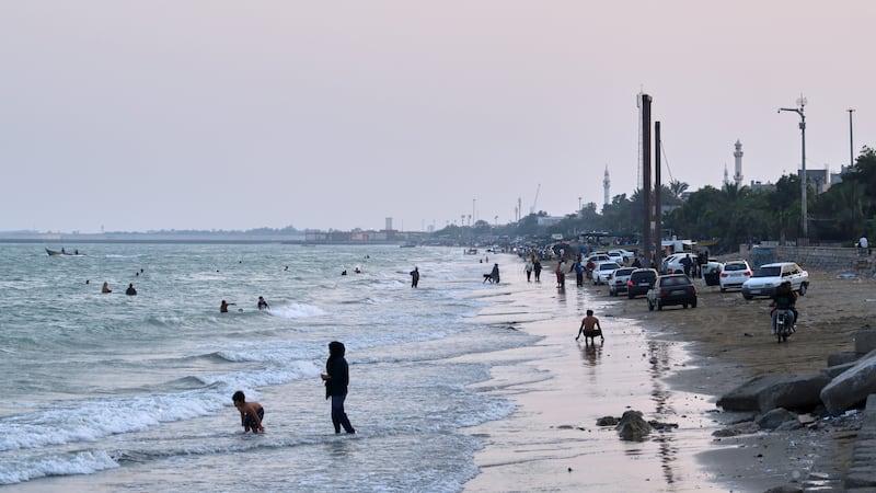 People swim and spend time along the shore of the Strait of Hormuz, off Bandar Abbas, Iran,...